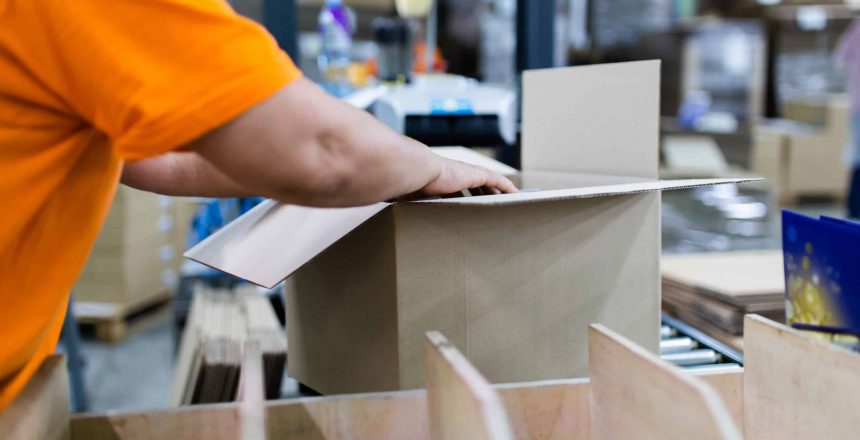 Close up shot of worker's hand preparing carton for printing in a modern printing house.